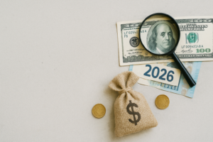 Magnet, billets et symbole dollar sur fond blanc, évoquant l'année 2026 et les finances.